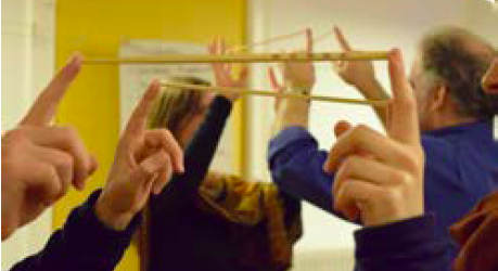 people holding up their fingers with a chopstick balanced between them